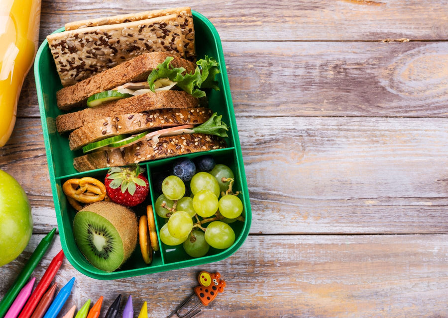 Healthy back-to-school lunchbox filled with sandwiches, grapes, kiwi, strawberries, crackers, and wholesome snacks for kids.