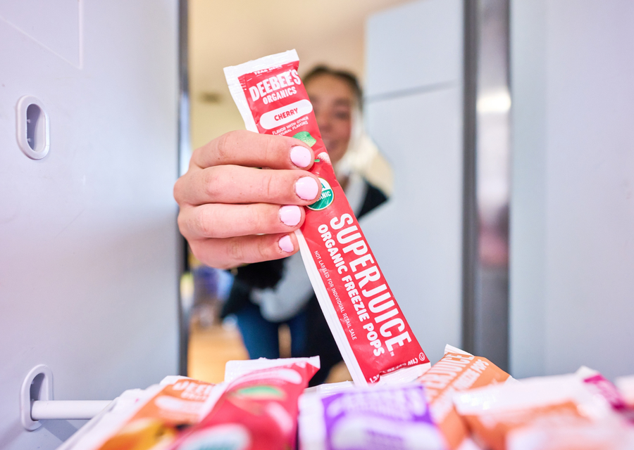 A DeeBee's Organics SuperJuice Cherry Freezie Pop being pulled from the freezer, ready for a refreshing family treat.
