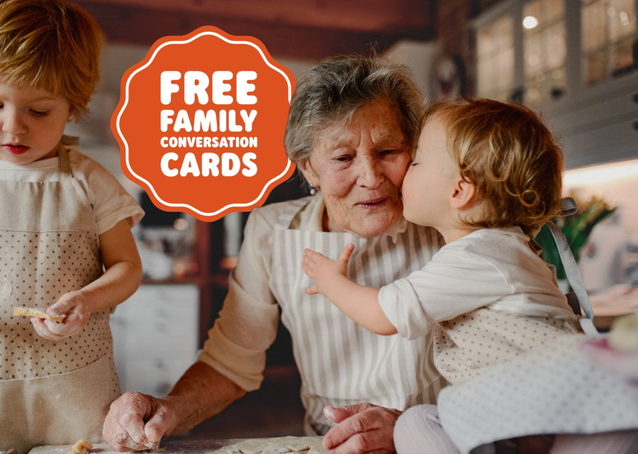Child kisses an older family member while baking together in a cozy kitchen, with text promoting free family conversation cards.