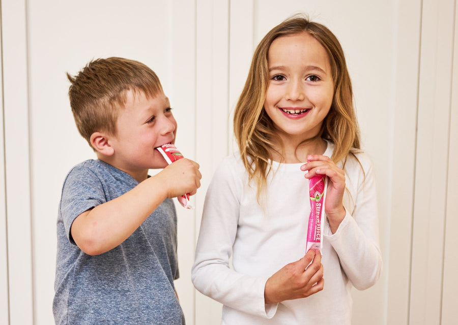 Two kids holding and enjoying DeeBee’s Organics freezie pops indoors.