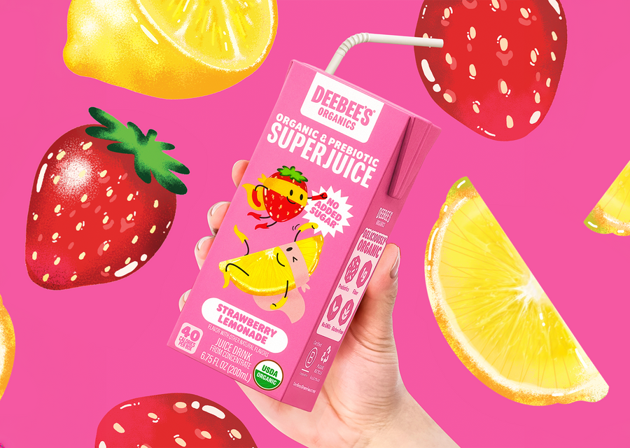 DeeBee’s Organic SuperJuice Strawberry Lemonade Prebiotic Juice Box held against a pink background with illustrated strawberries and lemon slices.