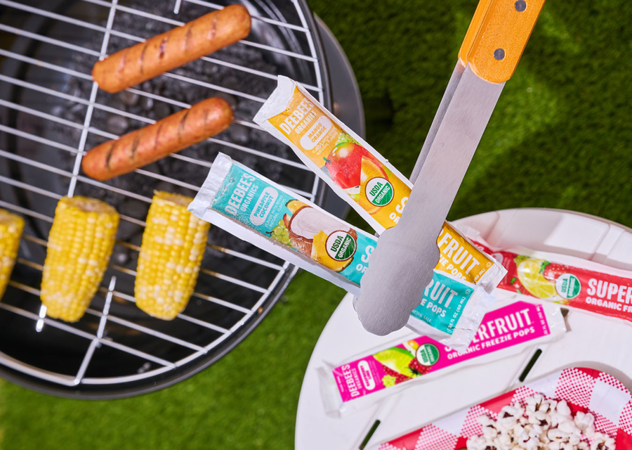 Organic freezer pops for kids by DeeBee’s Organics at a summer BBQ with grilled corn and hot dogs.