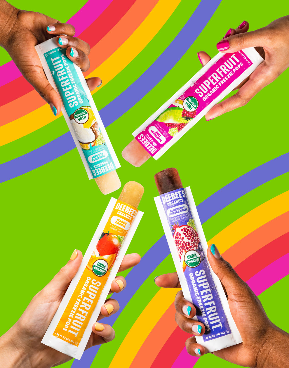 Four hands each holding a DeeBees Organics SuperFruit Freezie Pop on a green background with illustrated rainbows